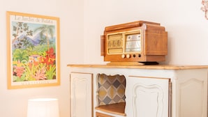 Een oude radio op een houten kast met een decoratieve wandversiering en een lamp.
