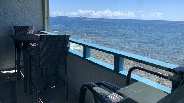 Un balcon doté de meubles en osier, donnant sur la mer.