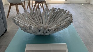 Un salon moderne avec un élément central original, un canapé de couleur turquoise et un panneau d’accueil encadré.