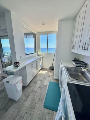 A modern kitchen with a view of the sea, a large window, and a built-in oven.