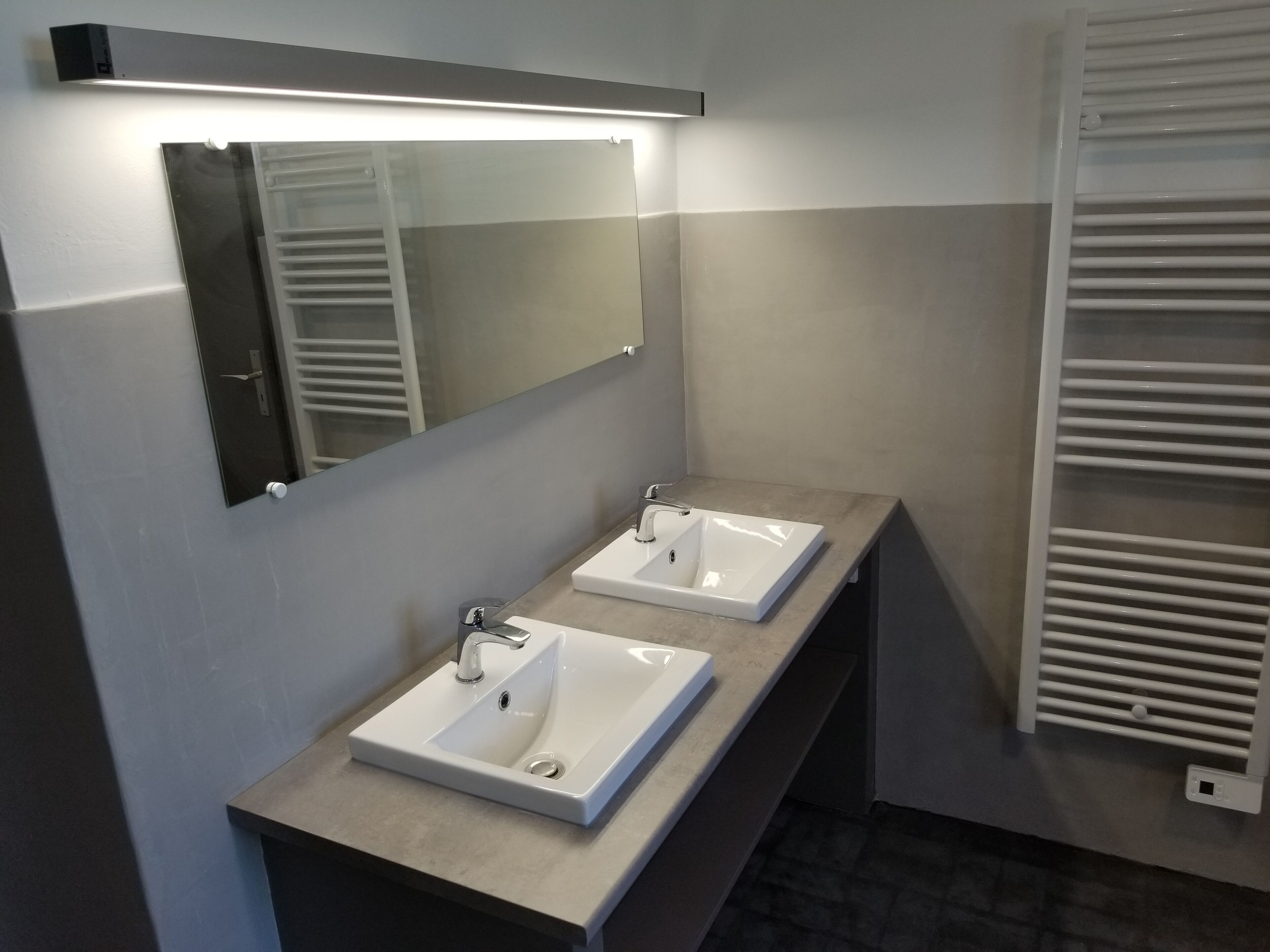 A modern bathroom with two sinks, a large mirror, and a towel rack.