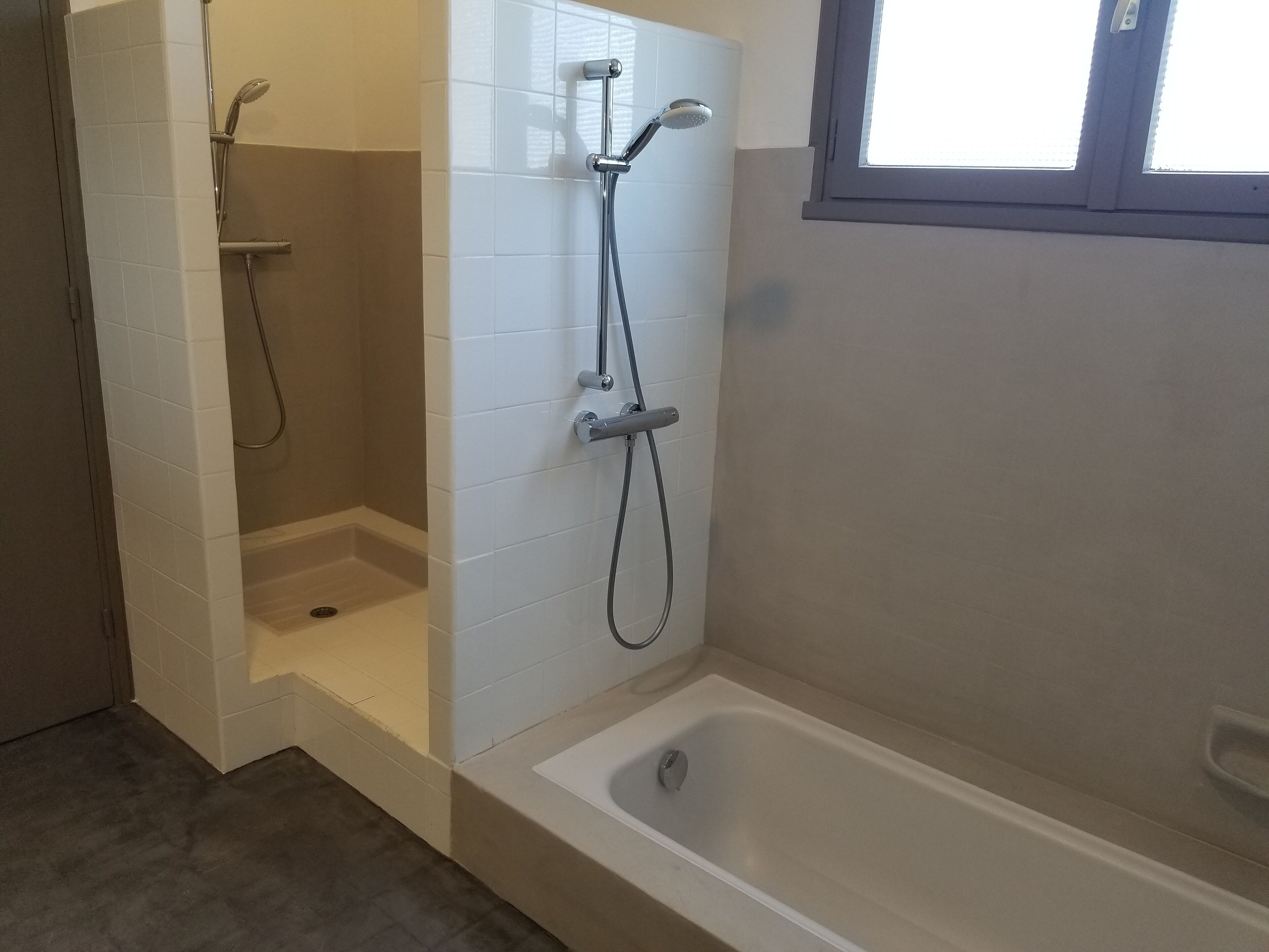 A bathroom with a shower, a bathtub, and a window.