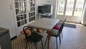 A small kitchen with a dining table, chairs, a refrigerator, and a window with a view of the outside. - Chambre parquet flottant (Savigné-lʼÉvêque)
