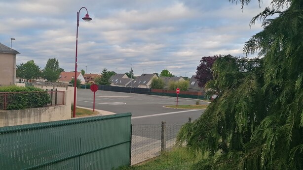 A residential street with houses, a stop sign, and a roundabout. - Chambre parquet flottant (Savigné-lʼÉvêque)