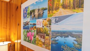A collage of travel photos on a wall, including a lake, forest, flowers, and a sign for 'Ely'. - Vacation UniquEly cottage #4 (Ely)