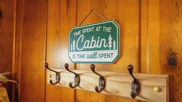 Een houten cabin-deur met een bordje waarop staat 'Tijd doorgebracht in de cabin is tijd goed besteed' en een kapstok met haken.