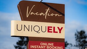 A sign advertising vacation booking services with features like online instant booking and self check-in. - Vacation UniquEly cottage #4 (Ely)