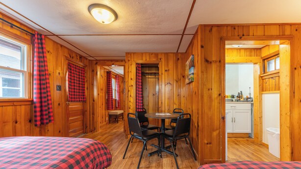 A cabin with two beds, a dining table, and a kitchen area. - Vacation UniquEly cottage #4 (Ely)