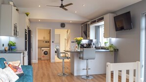 A modern kitchen with a dining area, a washing machine, and a TV mounted on the wall. - The Lookout - UK35022 (Hope-under-Dinmore)