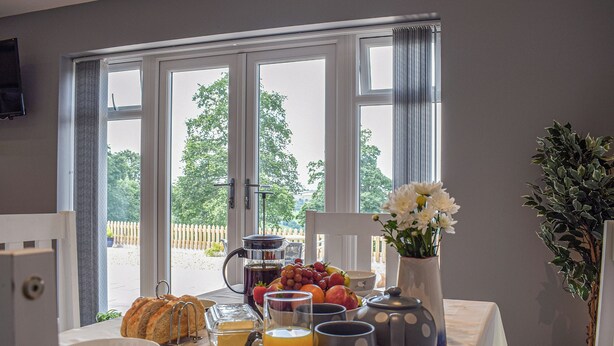 A breakfast table with a variety of food items, a coffee pot, and a vase of flowers. - The Lookout - UK35022 (Hope-under-Dinmore)