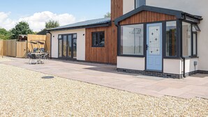 A modern house with a patio, a wooden fence, and a gravel driveway. - The Lookout - UK35022 (Hope-under-Dinmore)