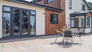 A modern house with large windows and a patio area with outdoor furniture. - The Lookout - UK35022 (Hope-under-Dinmore)
