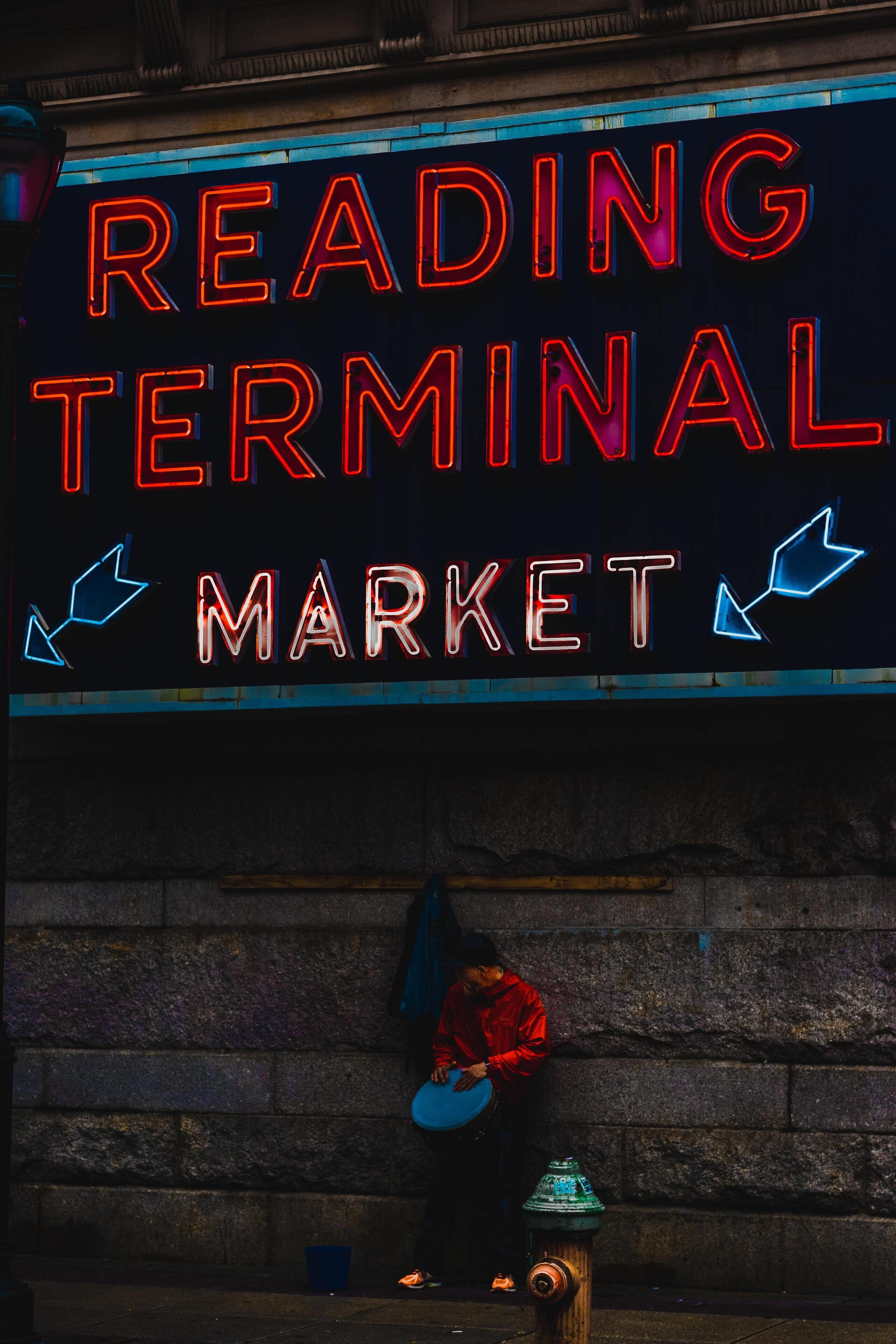 A neon sign reading "READING TERMINAL MARKET" with arrows pointing left and right.