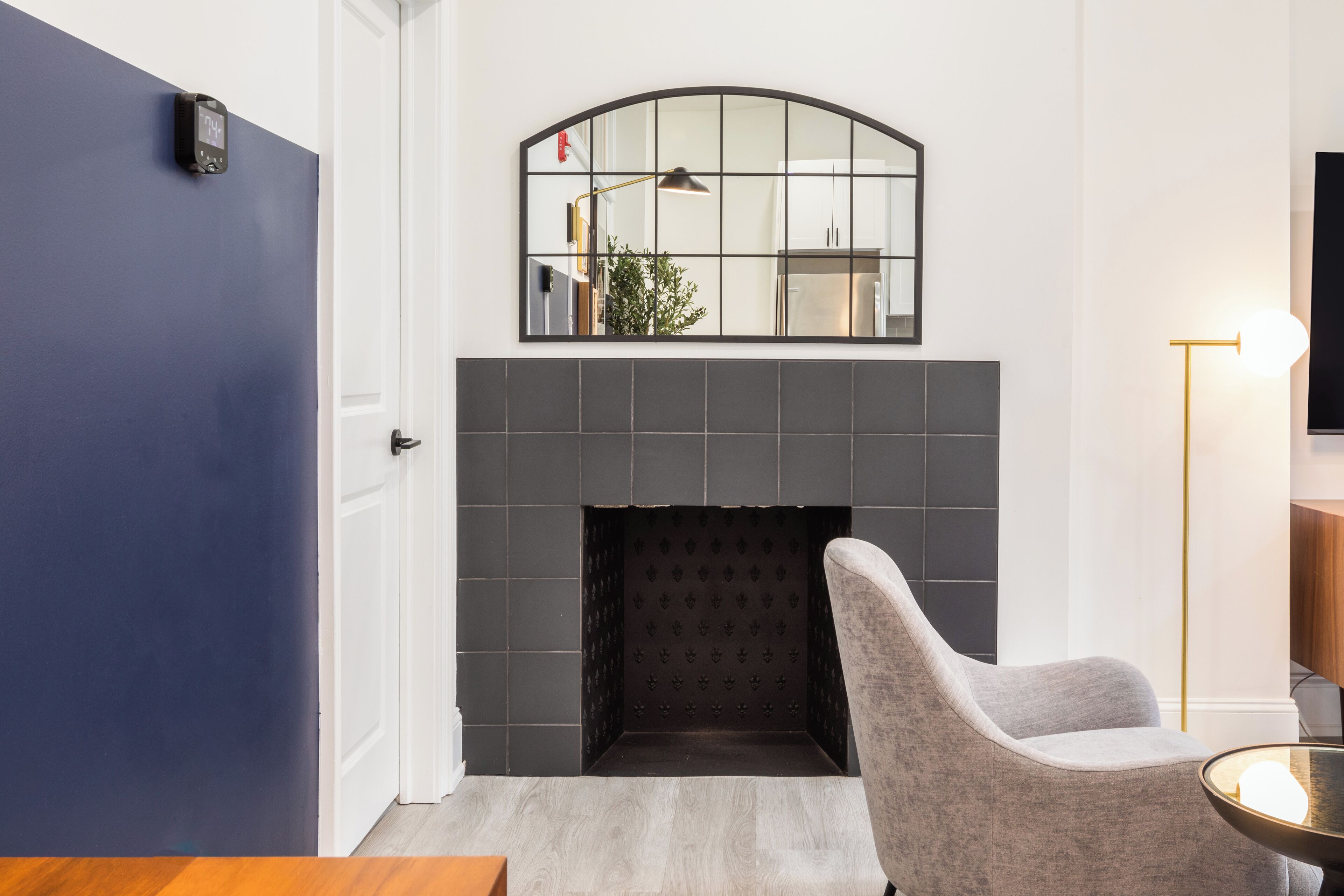 Una habitación moderna con chimenea, un sillón gris y una mesita.
