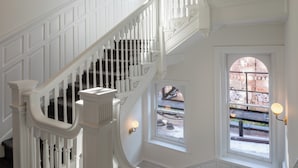 A white staircase with a curved design, leading to a landing with a window overlooking a street.