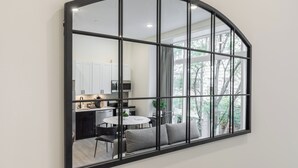 A modern kitchen with white cabinets, a dining area with a round table and chairs, and a large window with a view of trees.