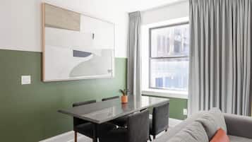 Una sala de estar moderna con una mesa de comedor, sillas, un sofá y un cuadro abstracto grande en la pared.