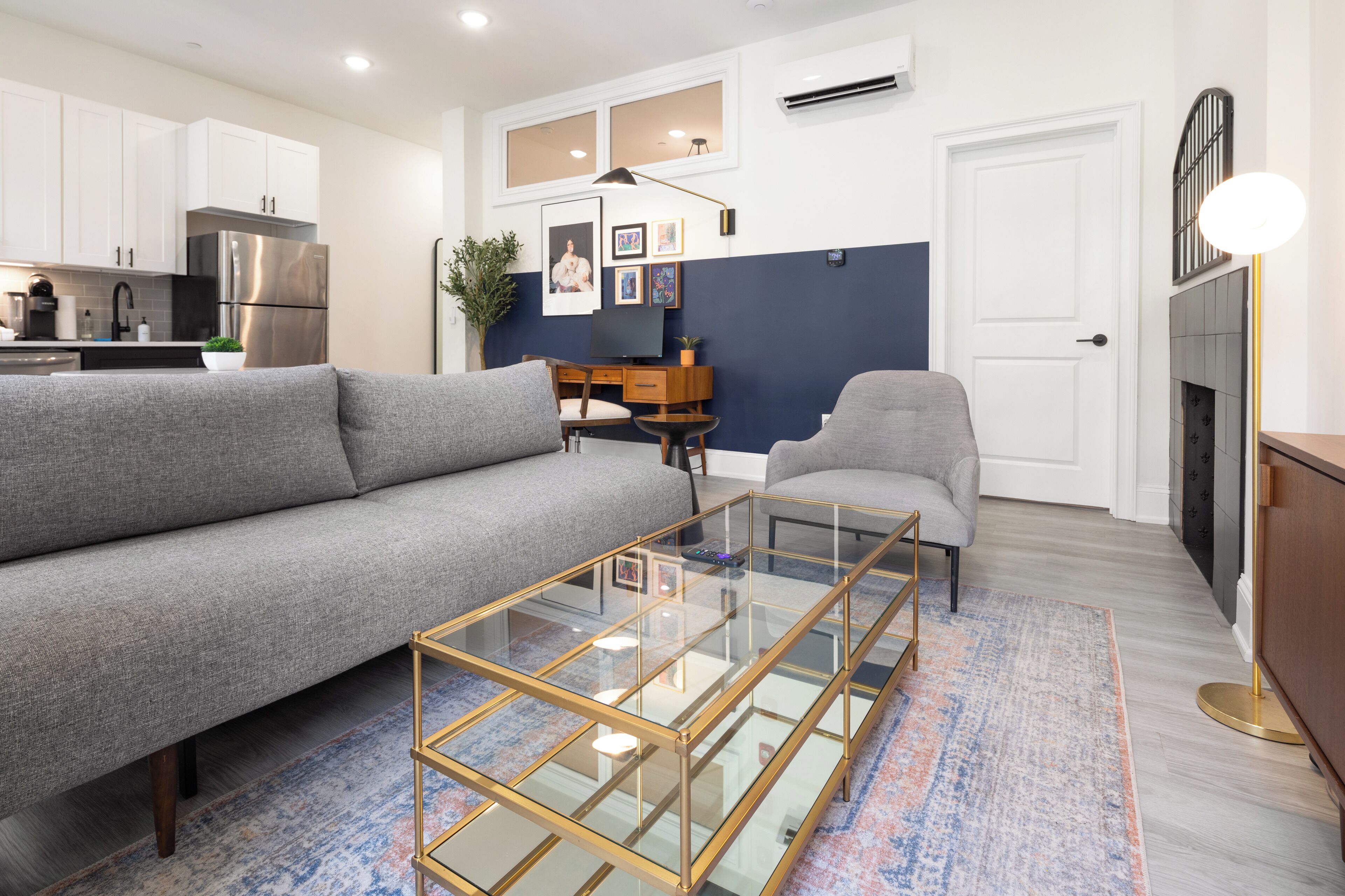 A modern living room with a grey sofa, a glass coffee table, and a fireplace.