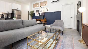 A modern living room with a grey sofa, a glass coffee table, and a fireplace.