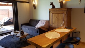 Un saló acollidor amb un sofà, una taula de fusta amb caires, un armari i una peça decorativa a la paret.