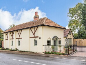 Un bâtiment à deux étages, doté d’un toit en tuiles, d’une cheminée et d’une entrée fermée par un portail.