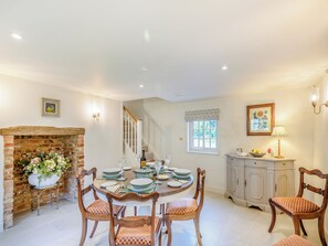 A dining area with a brick fireplace, a round table set for six, and a staircase leading to an upper floor. - 2 bedroom accommodation in Halton Holegate (Halton Holegate)