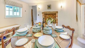 A dining room with a round table set for a meal, a fireplace, and a window with blinds. - 2 bedroom accommodation in Halton Holegate (Halton Holegate)