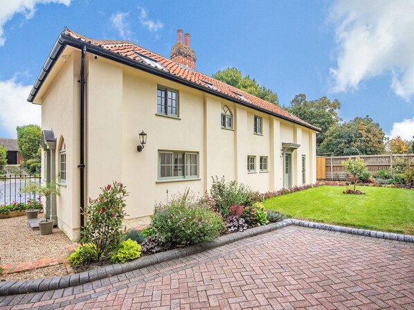 A two-story house with a brick chimney, a paved driveway, and a well-maintained garden. - 2 bedroom accommodation in Halton Holegate (Halton Holegate)