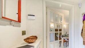 A hallway with a white counter, a wooden bowl, a mirror, a wall-mounted thermostat, and a door leading to a dining area. - 2 bedroom accommodation in Halton Holegate (Halton Holegate)