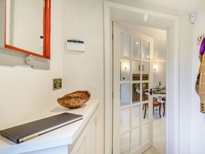 A hallway with a white counter, a wooden bowl, a mirror, a wall-mounted thermostat, and a door leading to a dining area. - 2 bedroom accommodation in Halton Holegate (Halton Holegate)