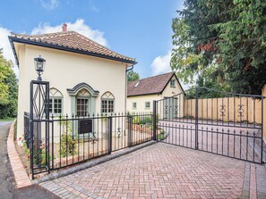 A two-story house with a tiled roof, a gated entrance, and a brick pathway leading to the door. - 2 bedroom accommodation in Halton Holegate (Halton Holegate)