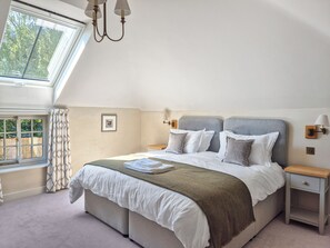 A bedroom with a large bed, a nightstand, a lamp, a window with curtains, and a picture on the wall. - 2 bedroom accommodation in Halton Holegate (Halton Holegate)