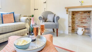 A living room with a sofa, armchair, fireplace, and a tray with a bottle and glasses. - 2 bedroom accommodation in Halton Holegate (Halton Holegate)