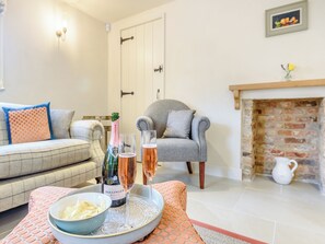 A living room with a sofa, armchair, fireplace, and a tray with a bottle and glasses. - 2 bedroom accommodation in Halton Holegate (Halton Holegate)