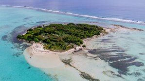 Vue aérienne d’une île tropicale avec une plage de sable et une végétation luxuriante.