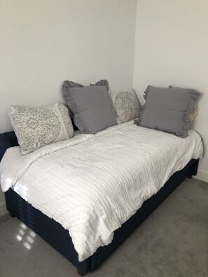 Restful retreat with a dark blue bed frame and white quilted bedspread, featuring four pillows.