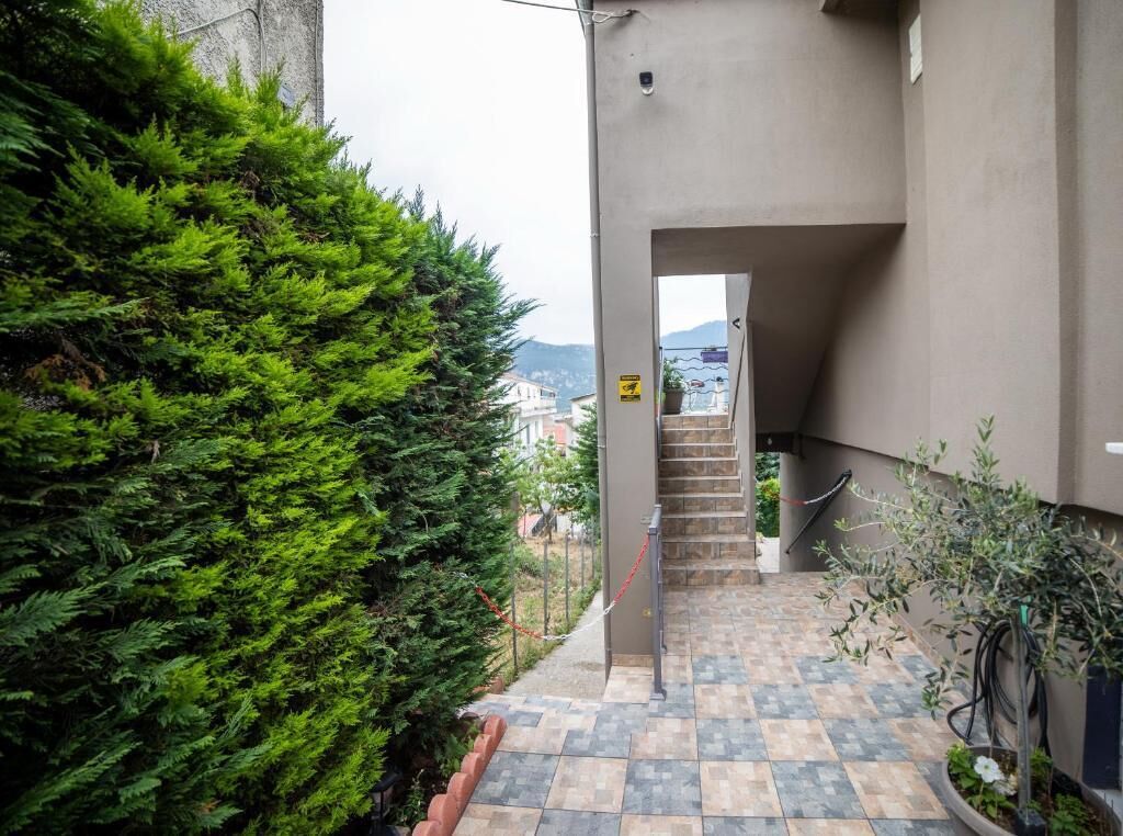 Un étroit couloir extérieur, dont le sol est carrelé, mène à un escalier.
