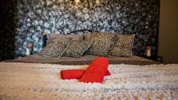 A bed with a patterned headboard, a white fluffy rug, and a red object on the rug.