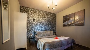 Una camera da letto con un letto, un comodino, una lampada a parete e un'ampia finestra.
