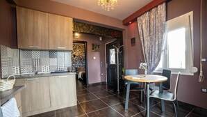 Una cucina moderna con piastrelle scure, mobili in legno e un'isola centrale. È presente una zona pranzo con un tavolo rotondo e sedie.