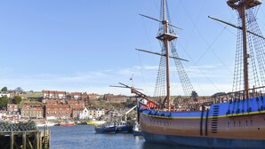 Un grand voilier était amarré dans un port, avec une ville en arrière-plan.