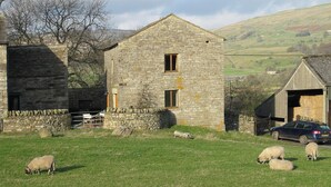 Un bâtiment en pierre avec deux fenêtres et une voiture garée devant.