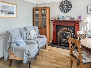 A living room with a fireplace, a sofa set, a wooden cabinet, and a clock on the wall.