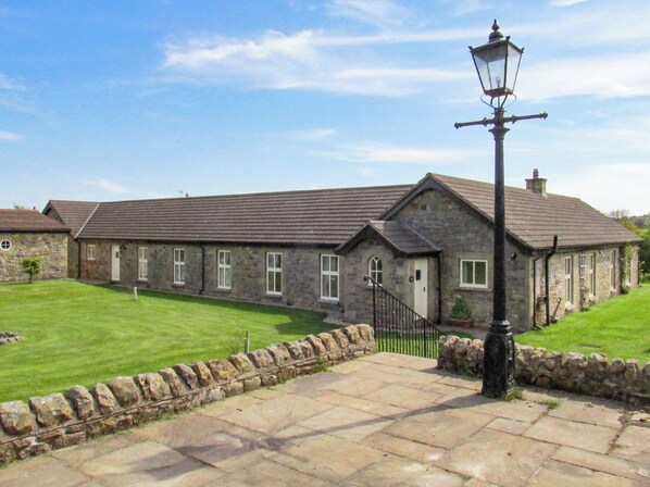 A stone building with a tiled roof, a paved entrance, and a traditional street lamp. - Owl Cottage High Weldon (Weldon Bridge, near Rothbury)