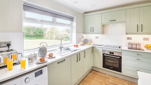 A modern kitchen with a large window, built-in appliances, and light-colored cabinets.