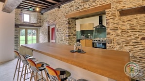 Una cucina rustica con pareti in pietra, un bancone in legno e un grande forno.