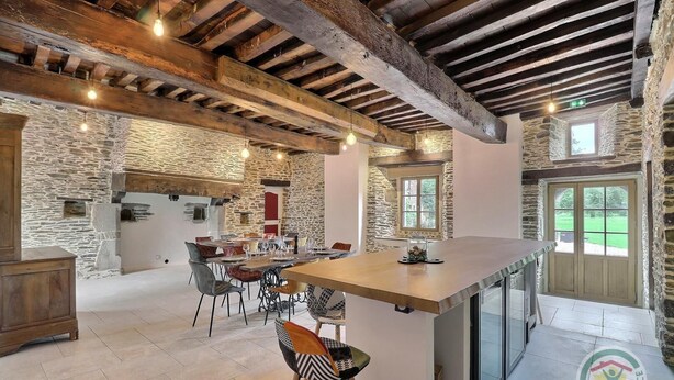 Una cucina rustica con travi a vista, pareti in pietra e una grande isola con sgabelli da bar.