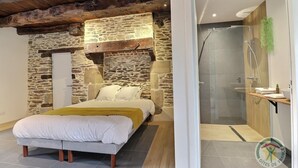 Una camera da letto con parete in pietra, un letto e un moderno angolo doccia.