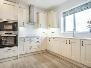 Cozinha moderna com armários brancos, eletrodomésticos de aço inoxidável e uma janela com vista.