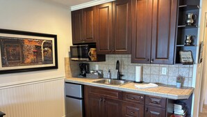 Una cocina con armarios de madera oscura, un lavamanos de acero inoxidable, un microondas y un refrigerador.